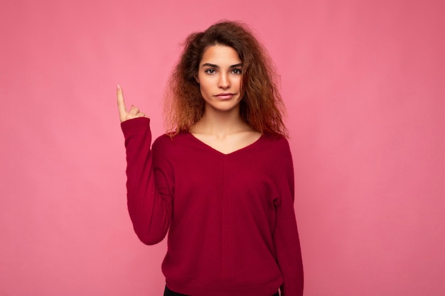 Foto de jovem séria linda morena ondulada com emoções sinceras vestindo rosa casual