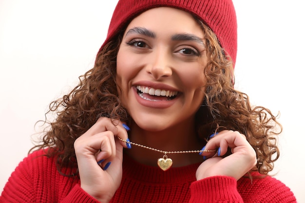 Foto de jovem sorridente com colar de coração nas mãos em vestido vermelho