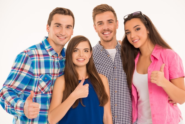 Foto de jovens alegres em pé mostrando os polegares para cima