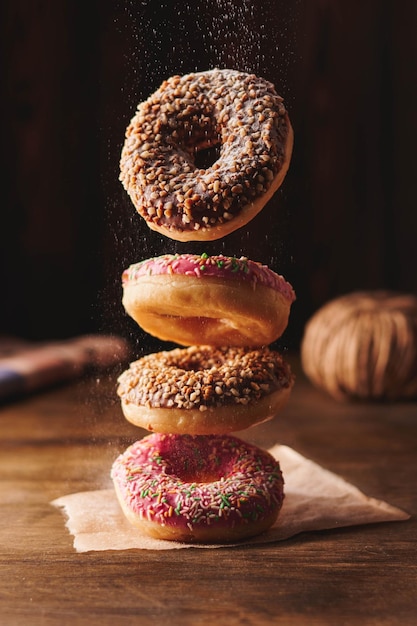 Foto de levitar vários donuts com pó voador no fundo de madeira