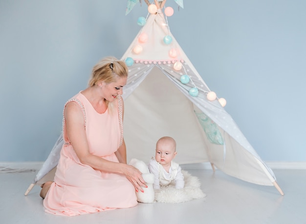 Foto de mãe brincando com seu filho em uma sala perto de uma barraca de crianças