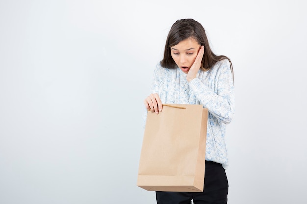 Foto de menina adolescente em suéter, olhando para dentro do saco de artesanato.