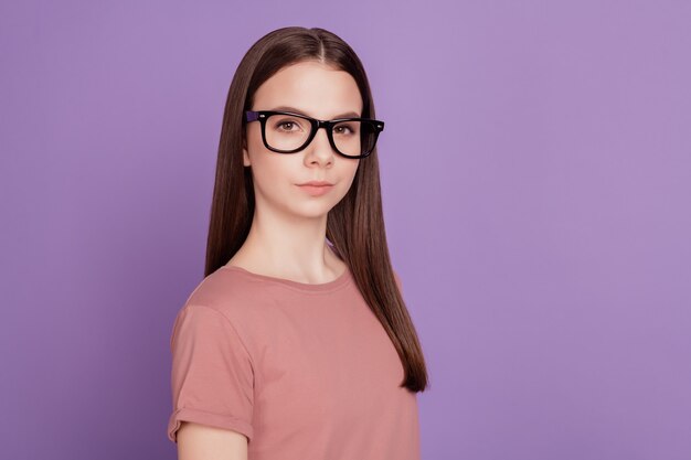 Foto de menina adolescente inteligente com óculos de boa aparência isolada sobre fundo violeta