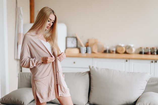 foto de menina com cabelo comprido abotoando as mãos em roupa de malha contra o pano de fundo do interior da casa