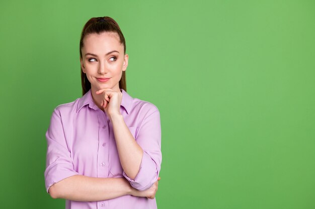 Foto de menina inteligente pensativa olhar copyspace tocar mão queixo pensar pensamentos decidir escolher decisão solução escolha vestir roupa lilás isolada sobre fundo de cor verde