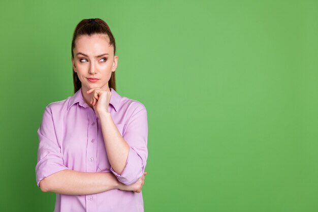 Foto de menina inteligente tocada mão queixo olhar copyspace pensar pensamentos decisão escolha vestir camisa violeta isolada sobre fundo de cor verde