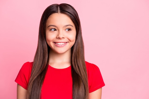 Foto de menina latina criança positiva olhando o espaço vazio sorrindo dentuço isolado sobre um fundo de cor rosa