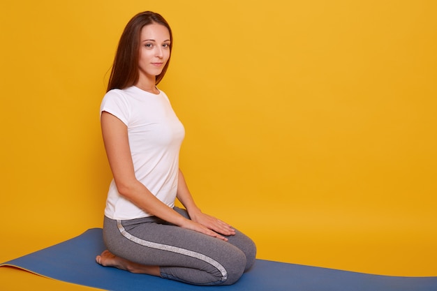 Foto de menina magro, sentado em posição de virasana e meditando em casa