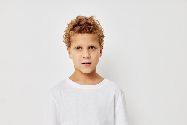 Foto de menino em uma camiseta branca posando divertida infância inalterada