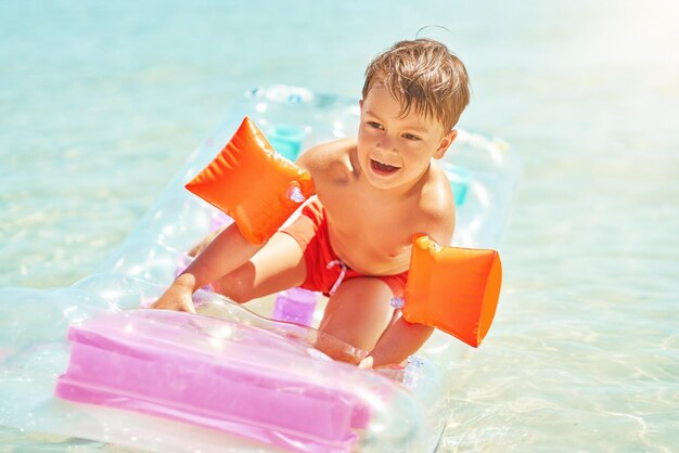 Foto de menino feliz nadando no colchão no mar vermelho