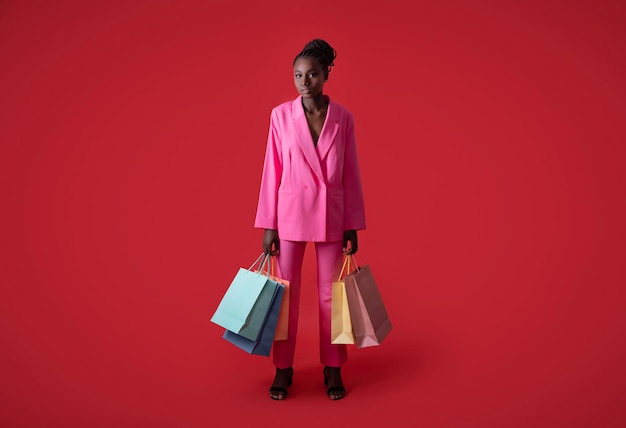 Foto de moda de jovem negra estilosa com sacolas de compras nas mãos