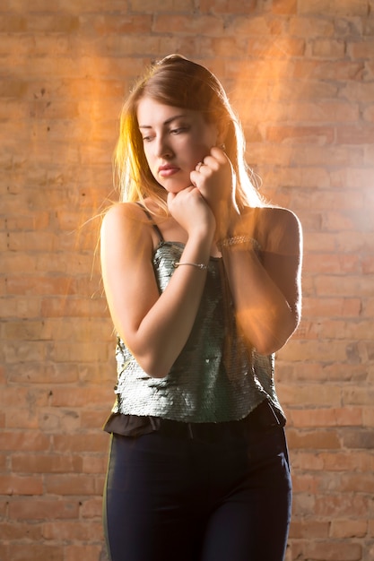 Foto de moda de mulher adorável posando em estúdio escuro com luz mista
