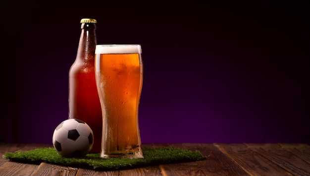Foto de mordomo e copo de bola de futebol de cerveja na grama verde