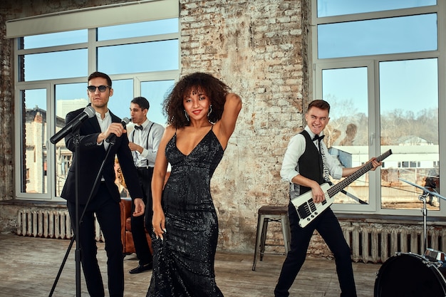Foto foto de muito grupo musical étnico em estúdio. músicos e uma solista afro-americana posando para a câmera durante um ensaio, loft