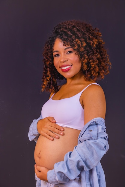 Foto de mulher afro-americana grávida feita em estúdio fotográfico com fundo preto