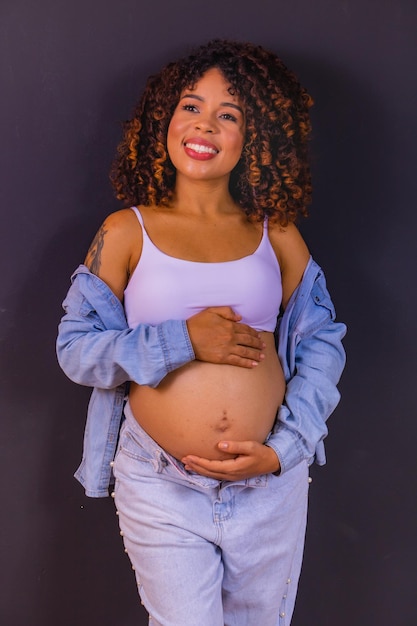 Foto de mulher afro-americana grávida feita em estúdio fotográfico com fundo preto