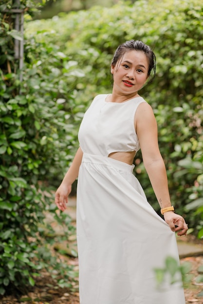 Foto de mulher asiática de vestido branco caminhando no parque ao ar livre