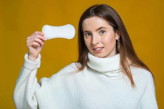 Foto de mulher atraente segura tampão de algodão e absorvente higiênico surpreendeu o olhar