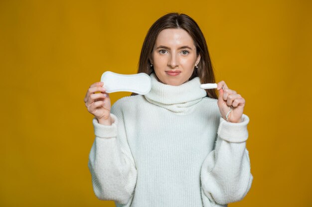 Foto de mulher atraente segura tampão de algodão e absorvente higiênico surpreendeu o olhar