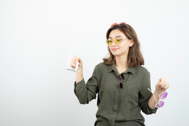 Foto de mulher bonita com óculos de sol coloridos em cima de branco. Foto de alta qualidade