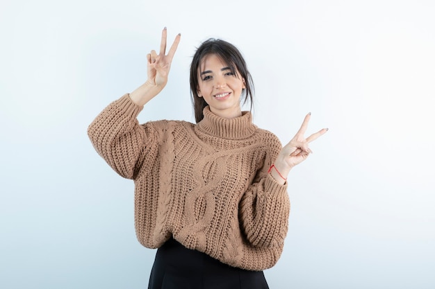 Foto de mulher bonita em pé de camisola de malha sobre fundo branco.