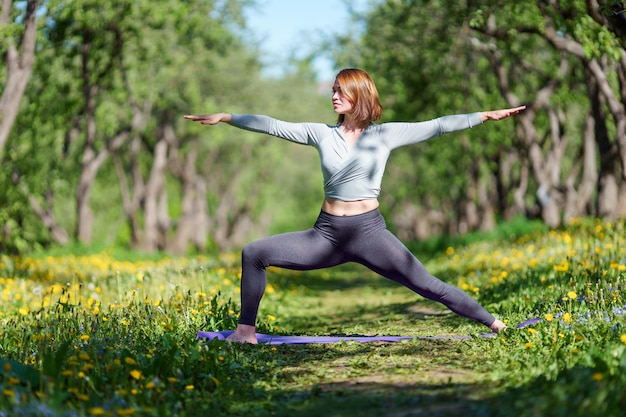 Foto de mulher com as mãos para os lados praticando ioga na floresta à tarde