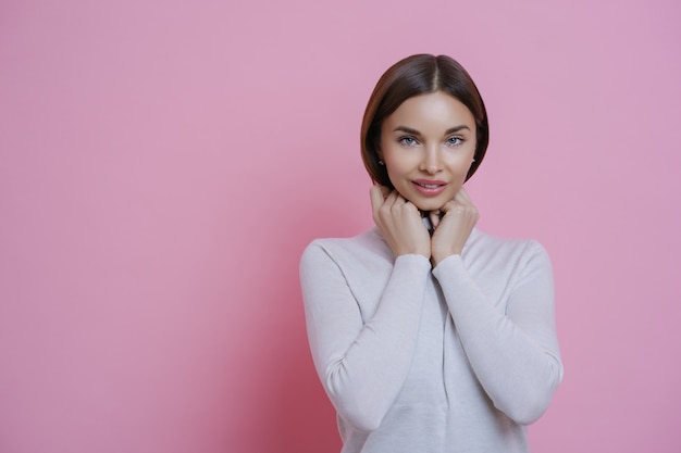 Foto de mulher de cabelo escuro satisfeito parece com expressão tímida na câmera