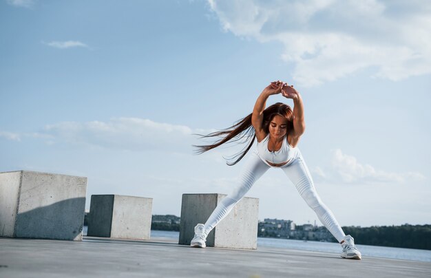 Foto de mulher esportiva fazendo exercícios de fitness perto do lago durante o dia