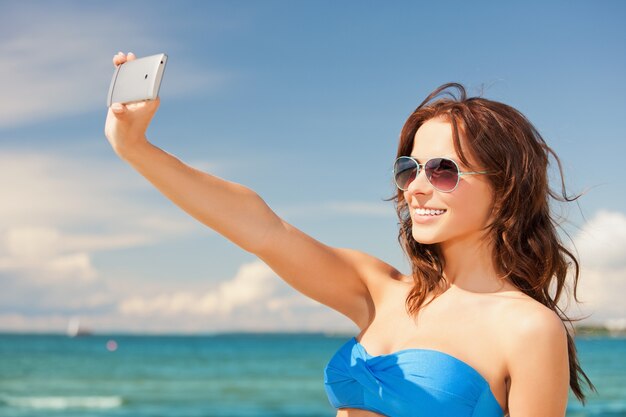 foto de mulher feliz com telefone na praia.