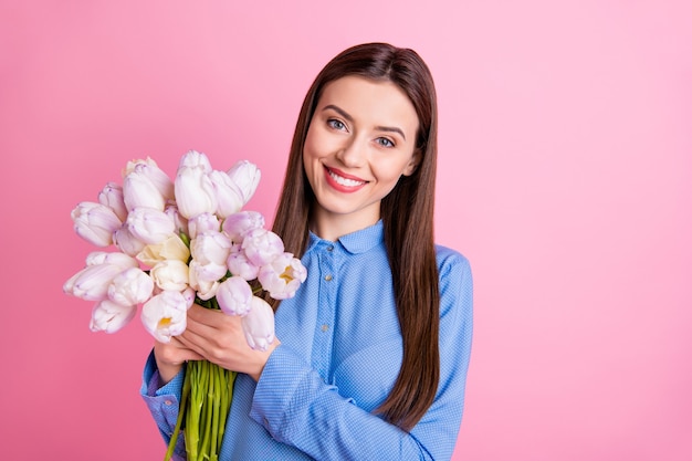 Foto de mulher fofa e feliz segurando um monte de tulipas brancas frescas grandes nas mãos