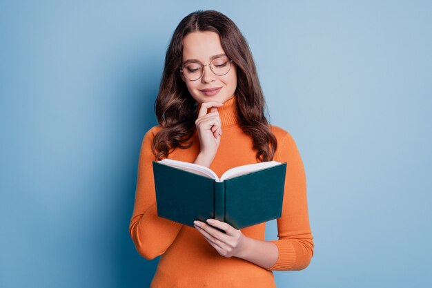 Foto de mulher inteligente lendo livro dedo queixo imaginar sobre fundo azul