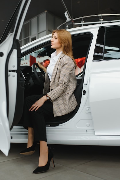 Foto de mulher jovem feliz sentada dentro de seu carro novo. Conceito para aluguel de carros