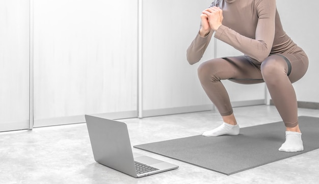 Foto de mulher praticando treinamento online em casa com o laptop.