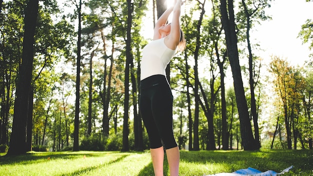 Foto de mulher sorridente de meia idade praticando ioga asana. persiga a meditação na natureza. equilíbrio e harmonia de corpo e mente