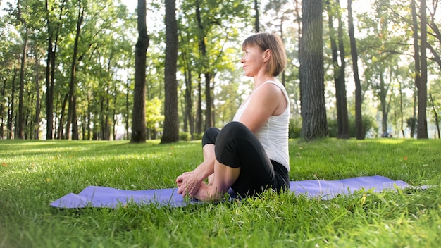 Foto de mulher sorridente de meia idade praticando ioga asana. persiga a meditação na natureza. equilíbrio e harmonia de corpo e mente