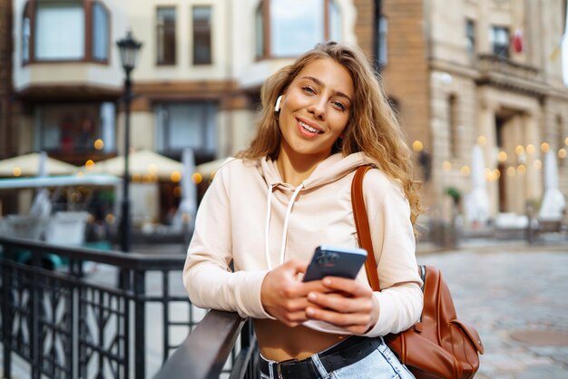 Foto de mulher usando smartphone Mulher enviando mensagens de texto na rua Mulher bonita passando tempo na cidade