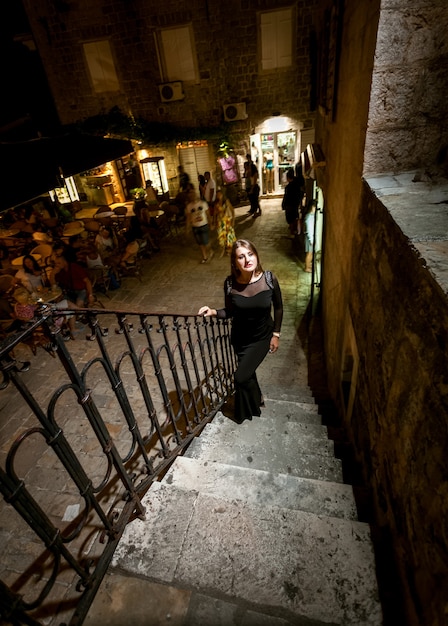 Foto foto de noite linda de uma mulher sexy em vestido subindo a escada na rua