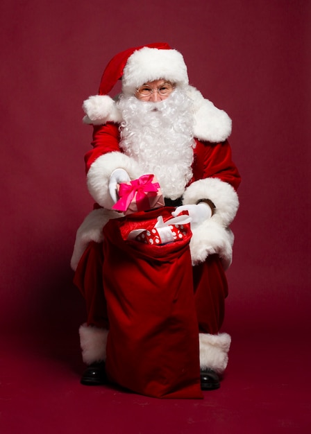 Foto de Papai Noel sorridente e feliz com caixas de presentes posando