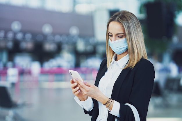 Foto de passageira adulta usando smartphone no aeroporto