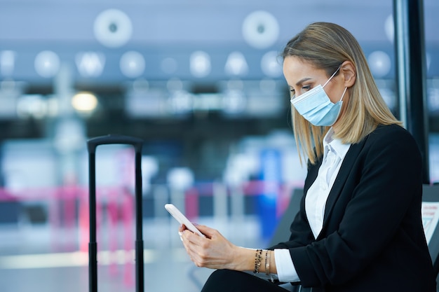 Foto de passageira adulta usando smartphone no aeroporto