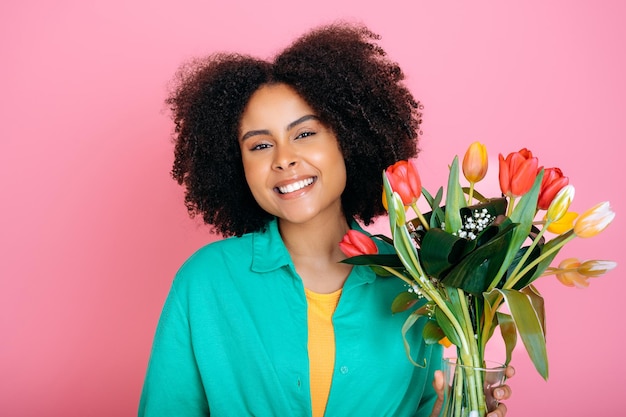 Foto foto de perfil de bonita optimista brunette penteado senhora segurar flores usar camisa branca isolado em fundo cor-de-rosa