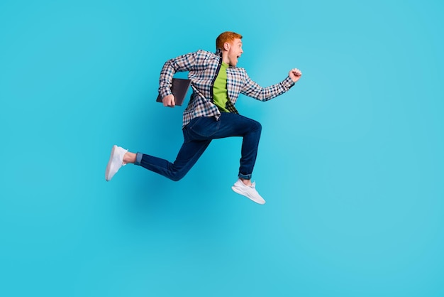 Foto de perfil de comprimento completo de um homem alegre correndo olhando para um espaço vazio isolado em fundo de cor turquesa