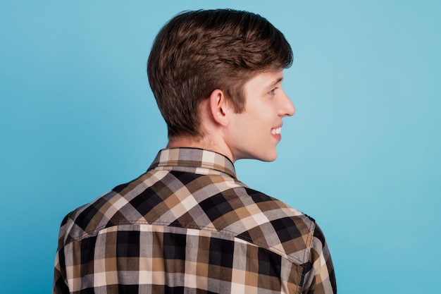 Foto de perfil de jovem alegre, bom humor, olhar espaço vazio barbearia isolada sobre fundo de cor azul