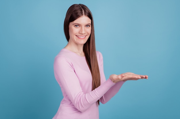 Foto de perfil de menina feliz sorriso positivo segurar a mão oferta da promoção de produto isolado fundo de cor azul