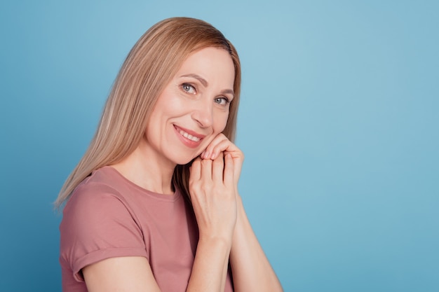 Foto de perfil de mulher atraente feliz sorriso positivo com as mãos tocando o queixo isolado fundo de cor azul