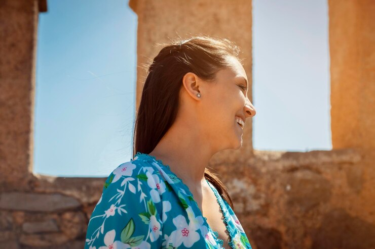 Foto foto de perfil lateral de uma jovem em um vestido de verão desfrutando da luz do sol quente