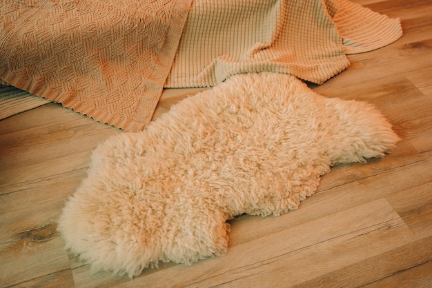 Foto de perto de um tapete de pele de ovelha no piso laminado de madeira dentro de casa