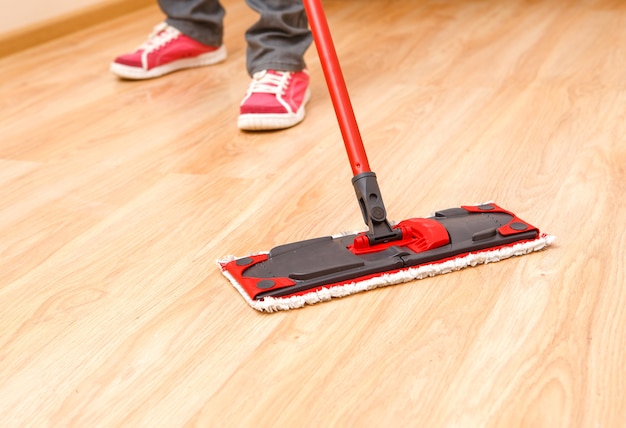 Foto de pés de homem com piso de esfregão no apartamento