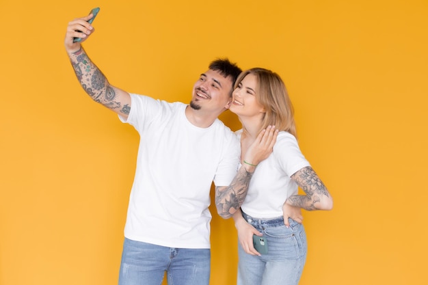 Foto de pessoas animadas positivas homem e mulher usando telefones celulares isolados sobre amarelo