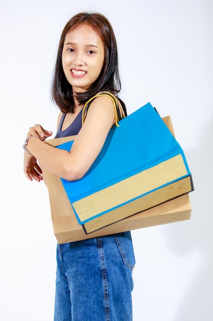 Foto de recorte de estúdio isolada de compradora de compras de mãe asiática compulsiva usando óculos de moda sorrindo e carregando sacolas de papel em fundo branco